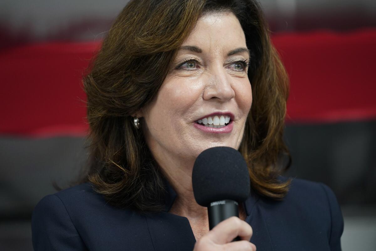 Kathy Hochul smiles and holds a microphone.