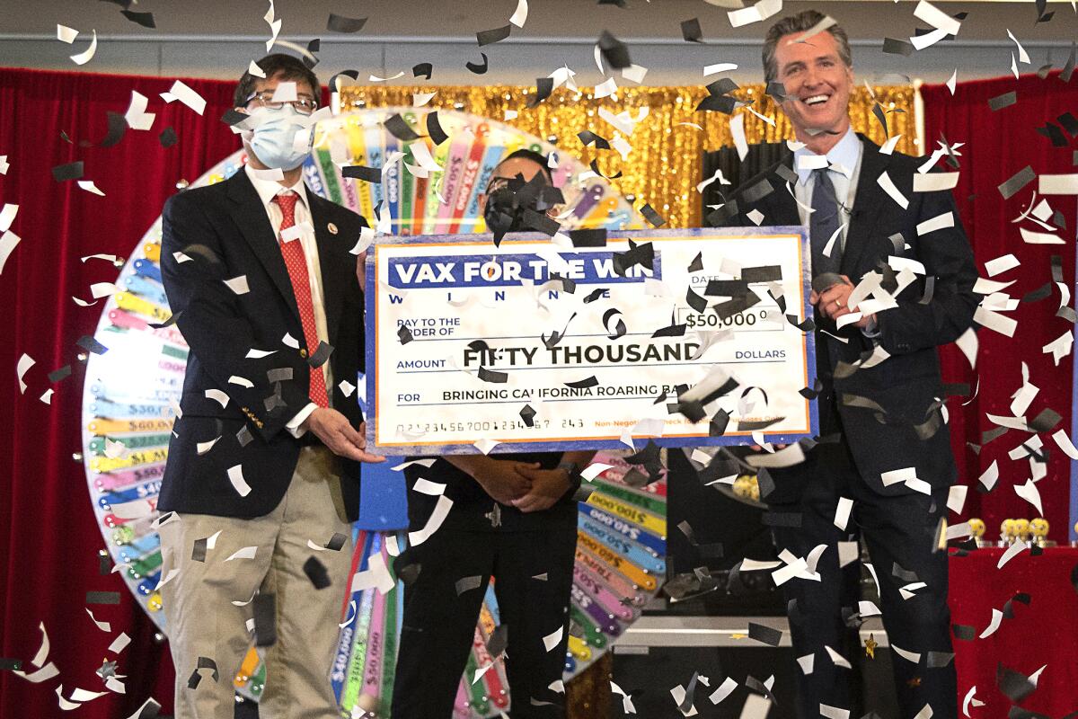 Three men hold a big mock check while confetti rains down on them.