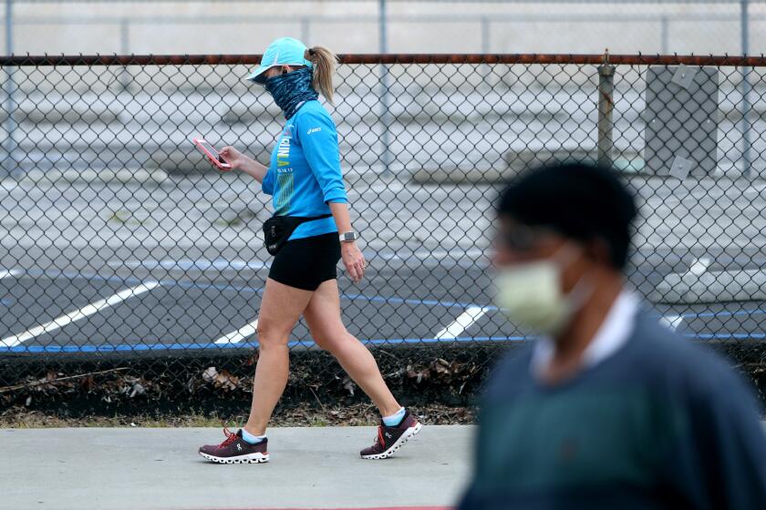 Because of the Coronavirus COVID-19 (SARS-CoV-2) pandemic, walkers on the 1900 block of Clark Ave. conform to social distancing norms while wearing face masks, in Burbank on Wednesday, April 8, 2020.