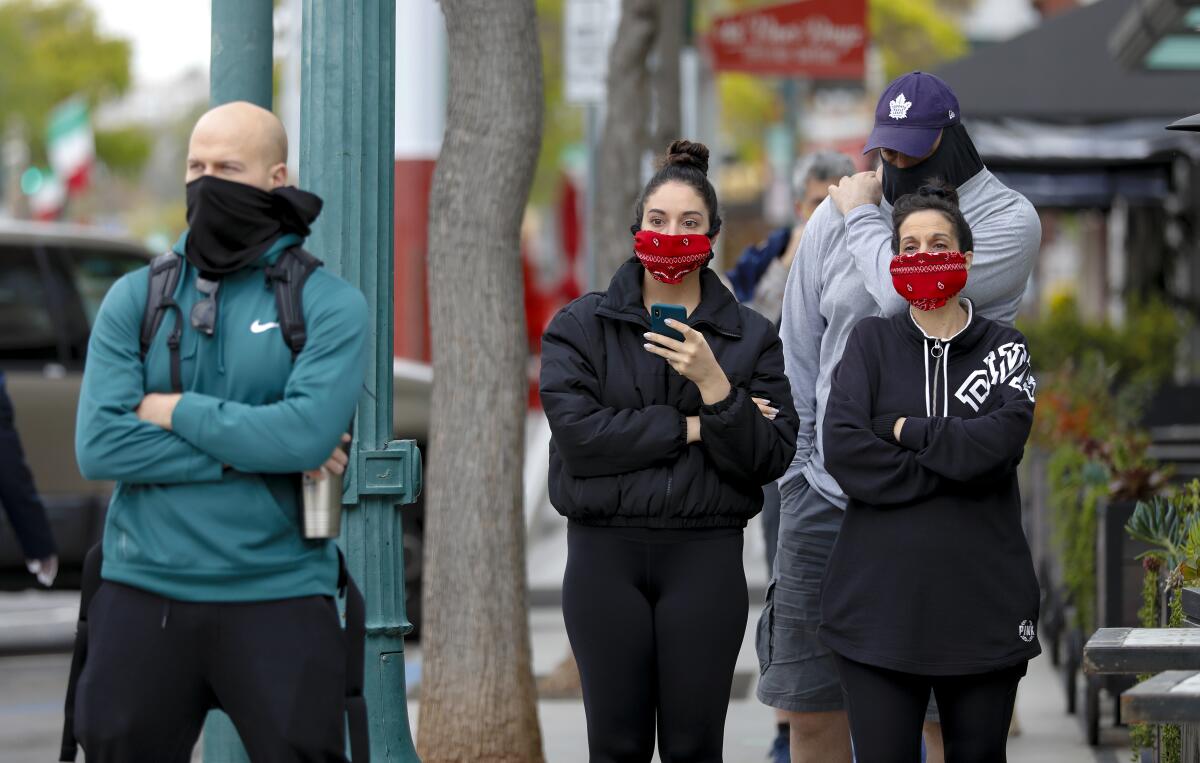 People standing in a line wear masks.