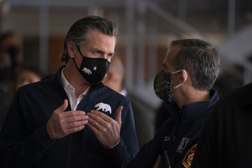 California Gov. Gavin Newsom, left, talks to Los Angeles Mayor Eric Garcetti during a news conference at a joint state and federal COVID-19 vaccination site set up on the campus of California State University of Los Angeles in Los Angeles, Tuesday, Feb. 16, 2021. (AP Photo/Jae C. Hong)
