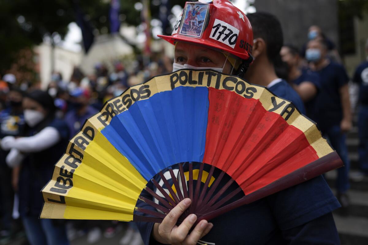 A woman holds a paper fan marked with a message that reads in Spanish: "Freedom for political prisoners now", during a gathering by opposition members to mark Youth Day, in Caracas, Venezuela, Saturday, Feb. 12, 2022. The annual holiday commemorates youths who accompanied heroes in the battle for Venezuela's independence. (AP Photo/Ariana Cubillos)