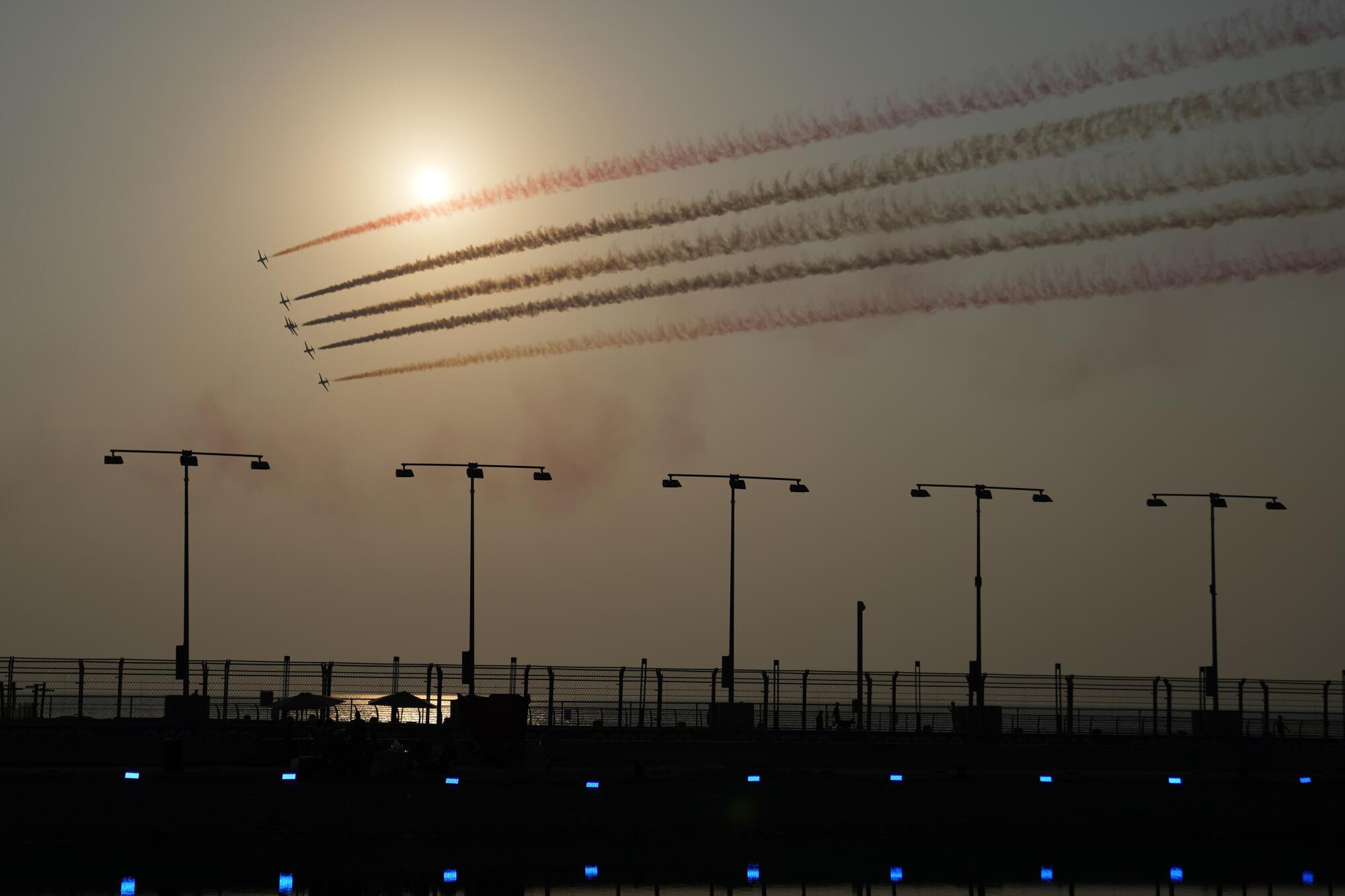 Jets trail streams of color over a racetrack in Saudi Arabia against hazy sun. 