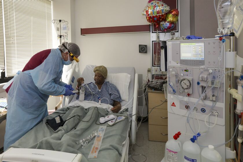 VICTORVILLE, CA - APRIL 29: Jennifer Stolpp, left, a dialysis nurse, prepares COVID-19 patient Janice Brown at Desert Valley Medical Group. Victorville, CA. (Irfan Khan / Los Angeles Times)