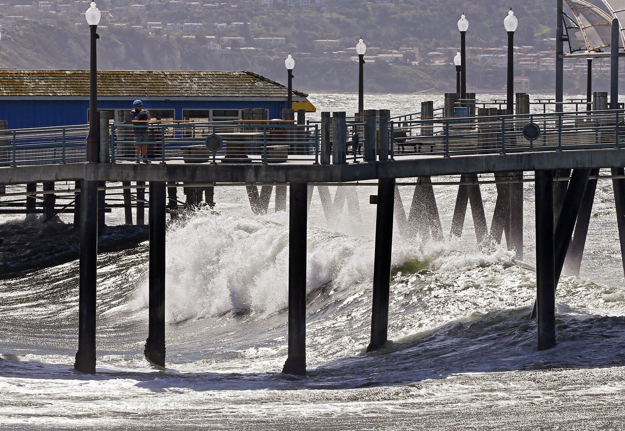A visitor to the Redondo Beach Pier watches waves roll ashore on Wednesday.
