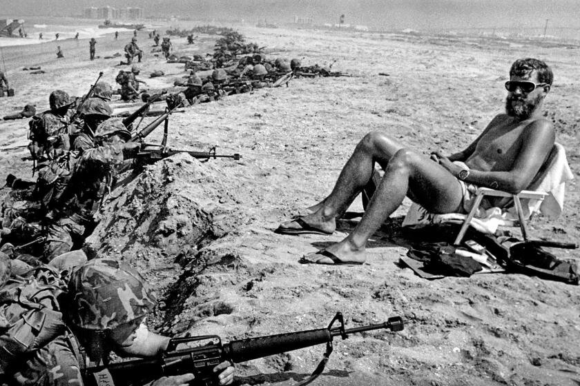June 22, 1978: Marine Reservists during a training amphibious landing at Coronado capture one spectator — a Navy specialist getting some rays after planting dummy explosives.