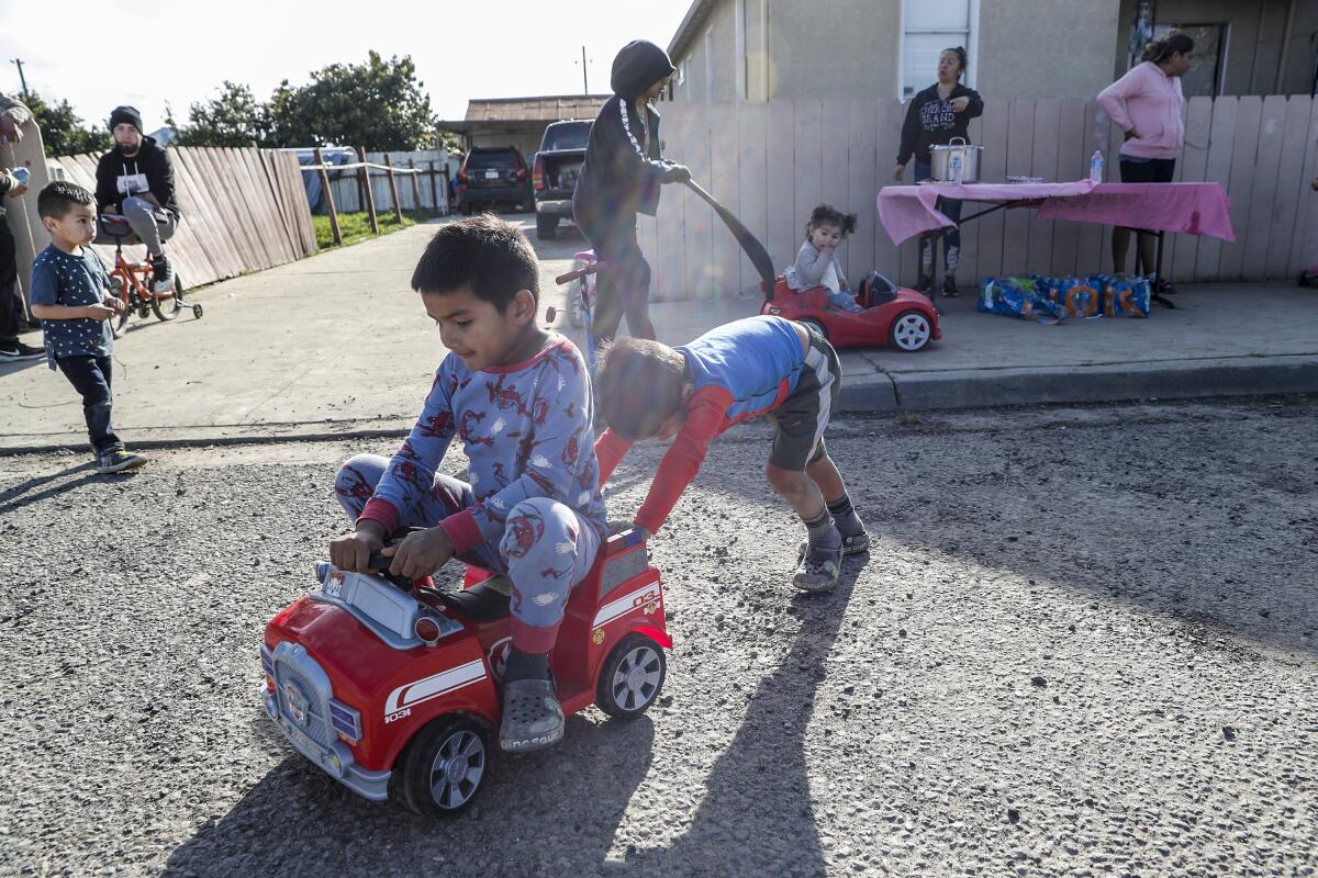 Children play on a road and sidewalk in front of a house. 