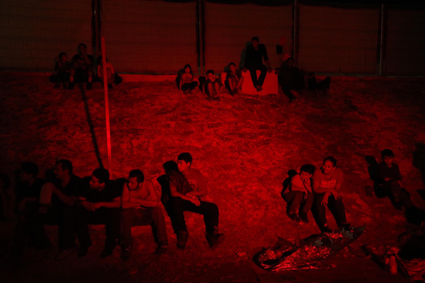 NUEVO LAREDO, MEXICO, CA - AUGUST 1, 2019 - - Asylum seekers keep an eye out for the arrival of four Chiapas-bound buses in the parking lot of an immigration check-point in Nuevo Laredo, Mexico on August 1, 2019. They were lit by an ambulance that was treating a sick child. When the buses finally arrived in Nuevo Laredo at about 1 a.m. Friday, nearly 200 migrants rushed to line up. Many were smiling, relieved. One woman exclaimed: ÒThank God we can go!Ó Migrants were released into cartel-weary Nuevo Laredo this week stayed and slept in the parking lot of the immigration check-point for days struggling to find food, water and other necessities. Many headed back to their home country. (Genaro Molina / Los Angeles Times)