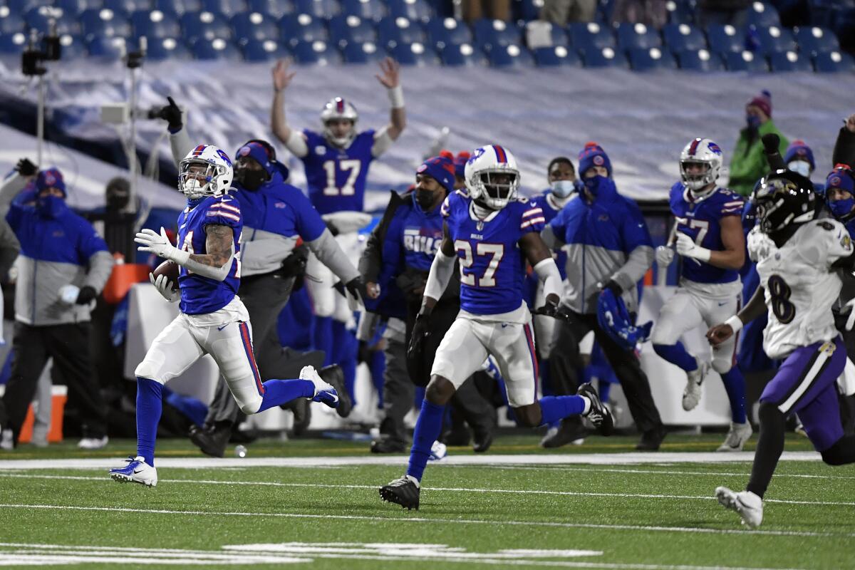 Bills cornerback Taron Johnson, left, runs away from the Ravens' Lamar Jackson (8) after intercepting his pass for a TD.