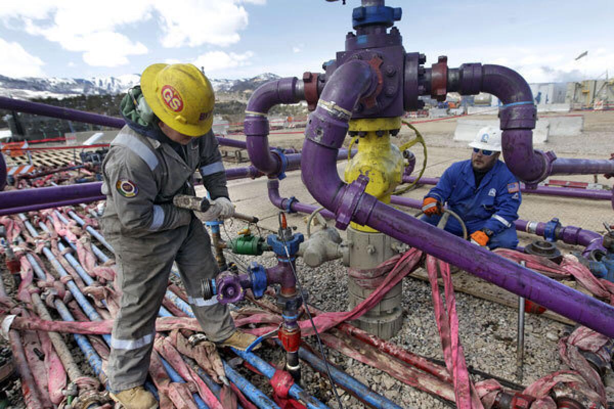 Workers tend to a well head at a hydraulic fracturing operation in Rifle, Colo.