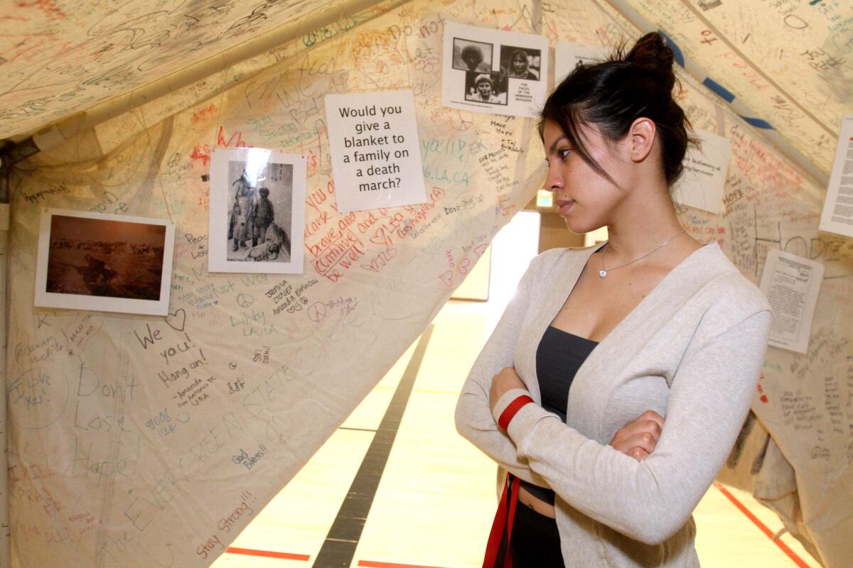 Glendale High School senior Kassandra Figueroa looks at information inside a genocide tent provided to the school by I-ACT on Thursday, March 10, 2016. I-ACT provided six tents with information about genocides in Armenia 1915, Holocaust 1938, Cambodia 19075 and present-day Darfur.