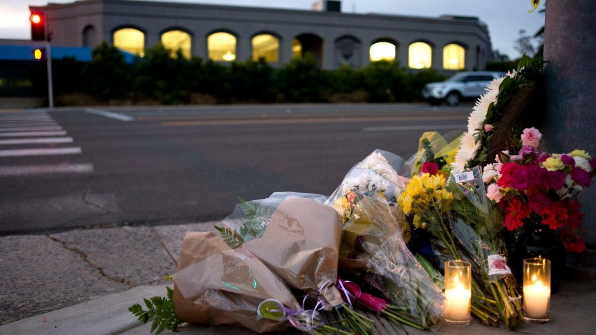 Flowers and candles sit at a makeshift memorial across the road from the Chabad of Poway synagogue on Saturday following an attack that left one person dead and three injured.