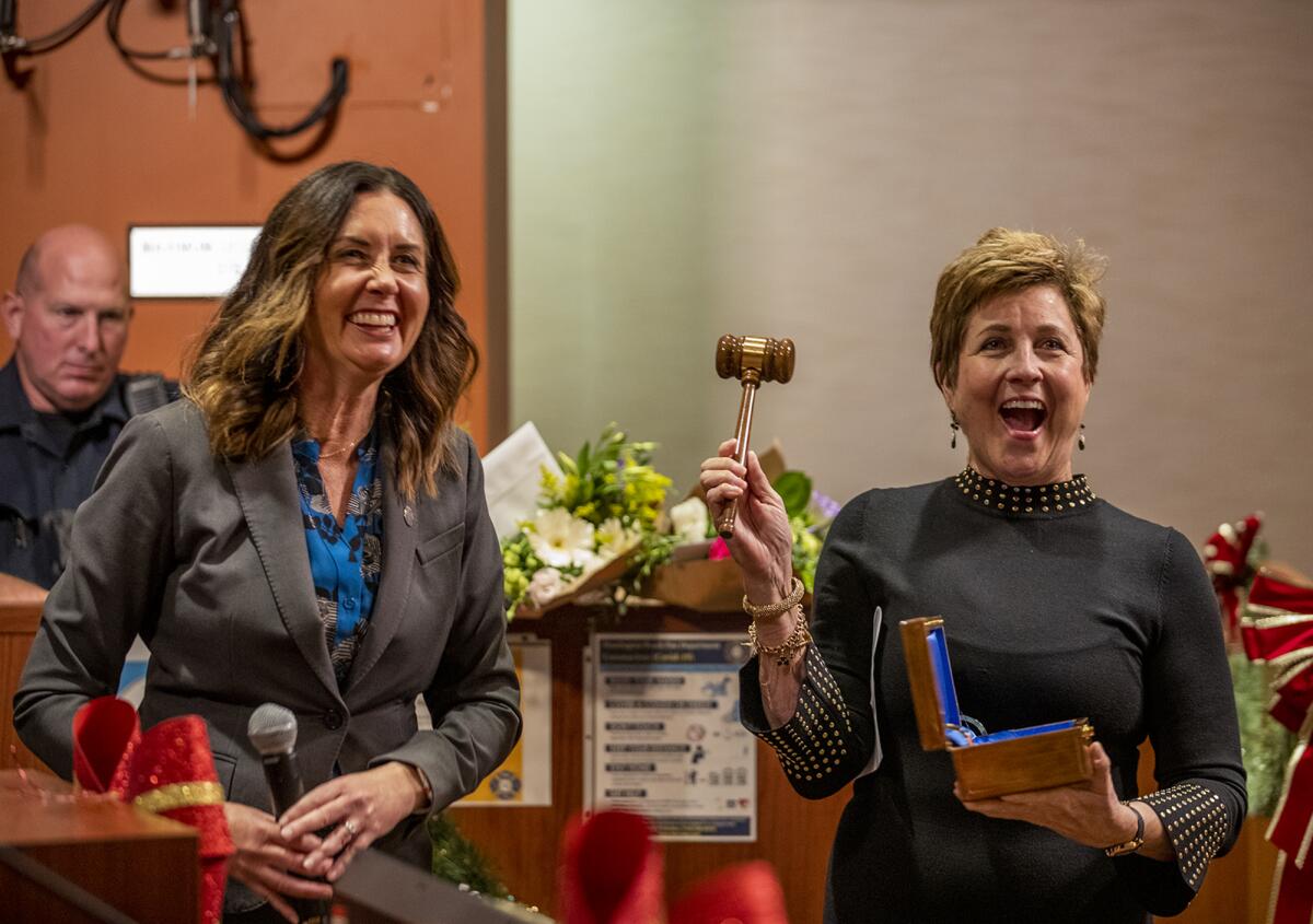 Outgoing Mayor Kim Carr, left, presents Barbara Delgleize with a gavel after she was sworn in as the new mayor Tuesday night.