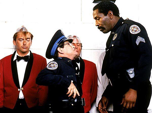 Tim Kazurinsky as Sweetchuck looks up at Bubba Smith as Hightower in "Police Academy 3." See obituary