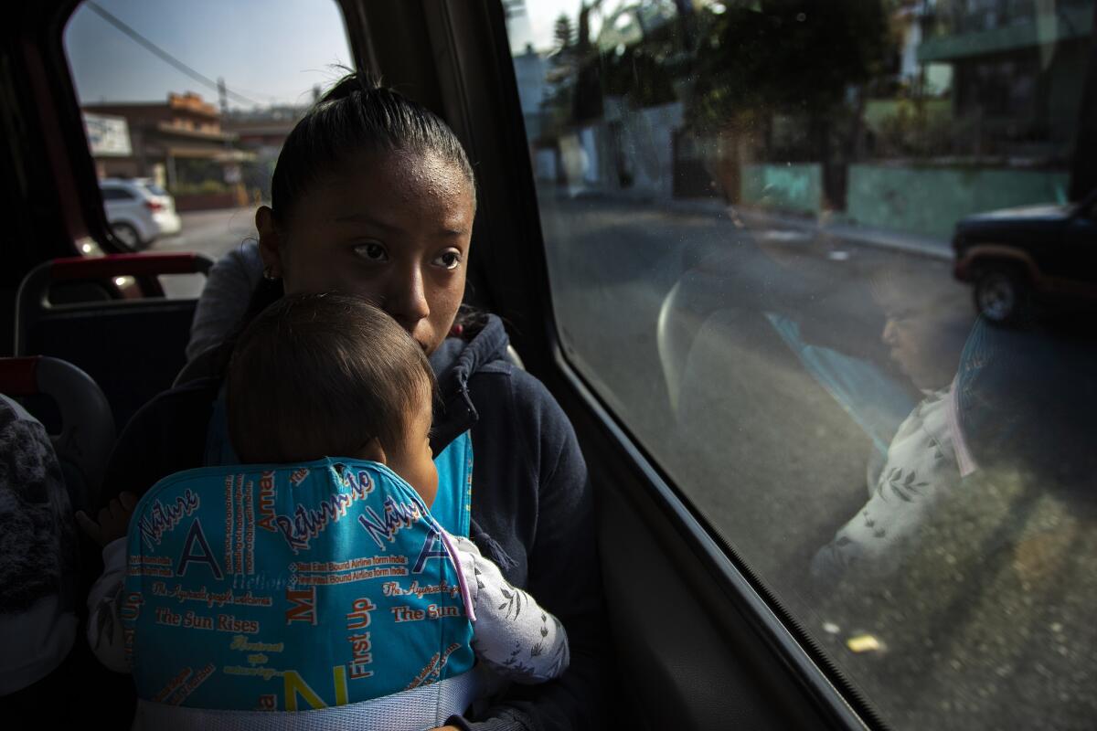 Diana holds her baby sister Bernardethe as she travels by bus with her brother Davis and mother Dalila Pojoy to the border.