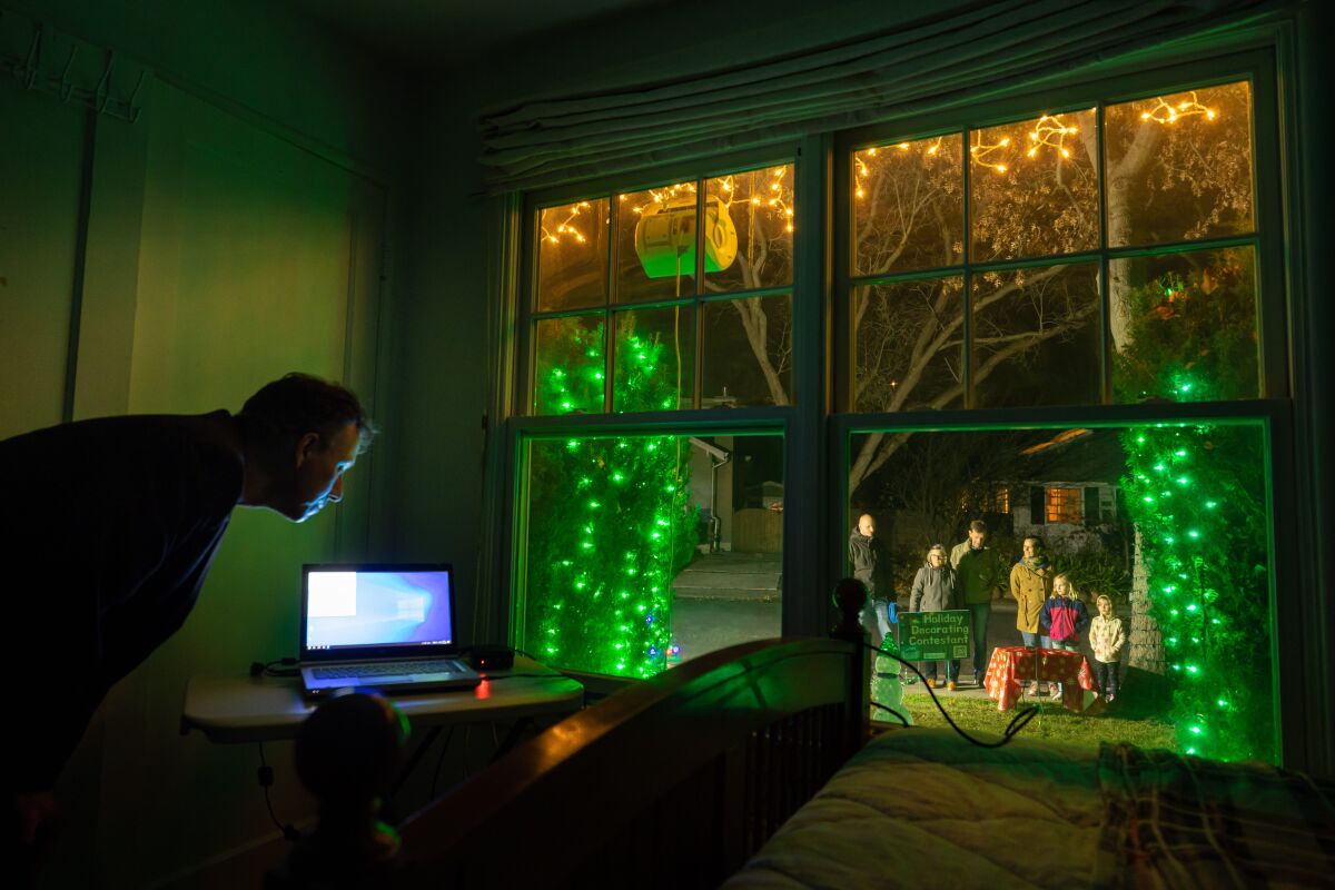 A man looks at a computer next to a picture window overlooking his decorated courtyard.