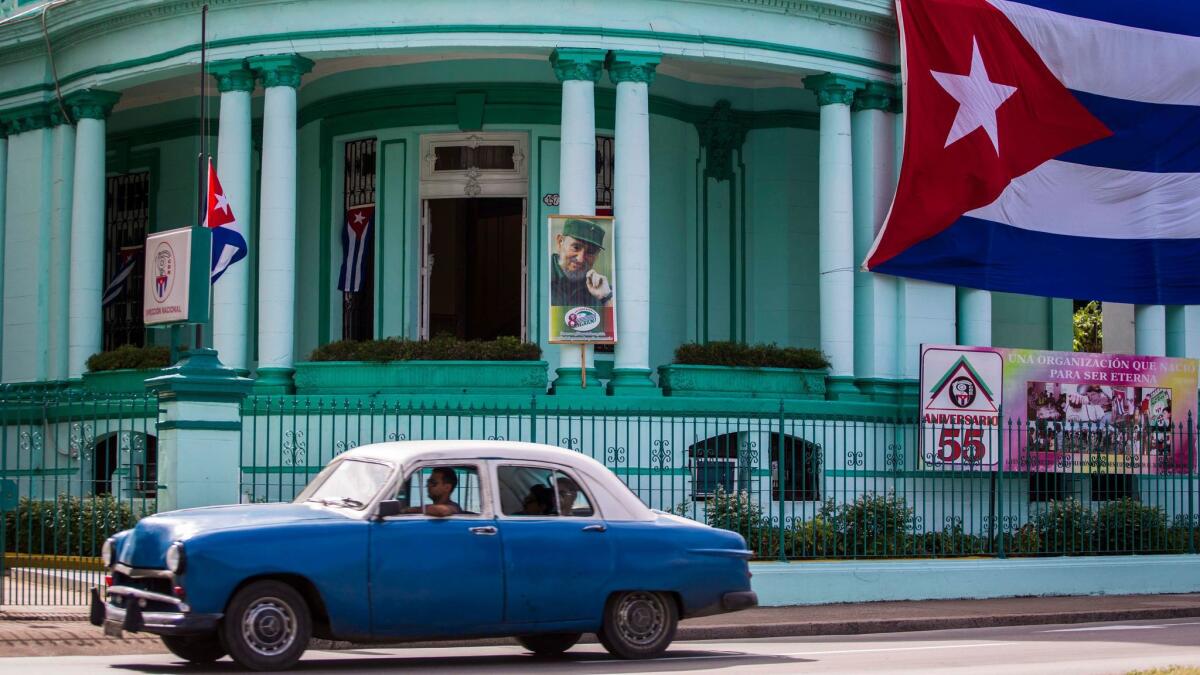 A Cuban flag flies at half staff, left, and a picture of former President Fidel Castro adorns the headquarters of the Committees for the Defense of the Revolution in Havana on Nov. 26, 2016.