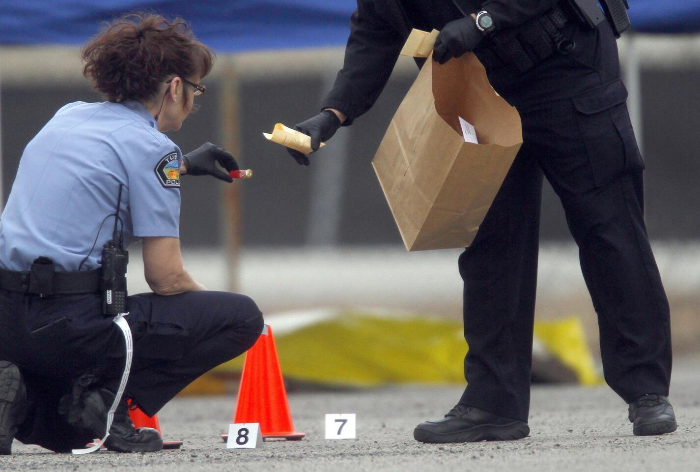 A Tustin crime scene investigator catalogs shell casings in the parking lot of the Micro Center computer store.