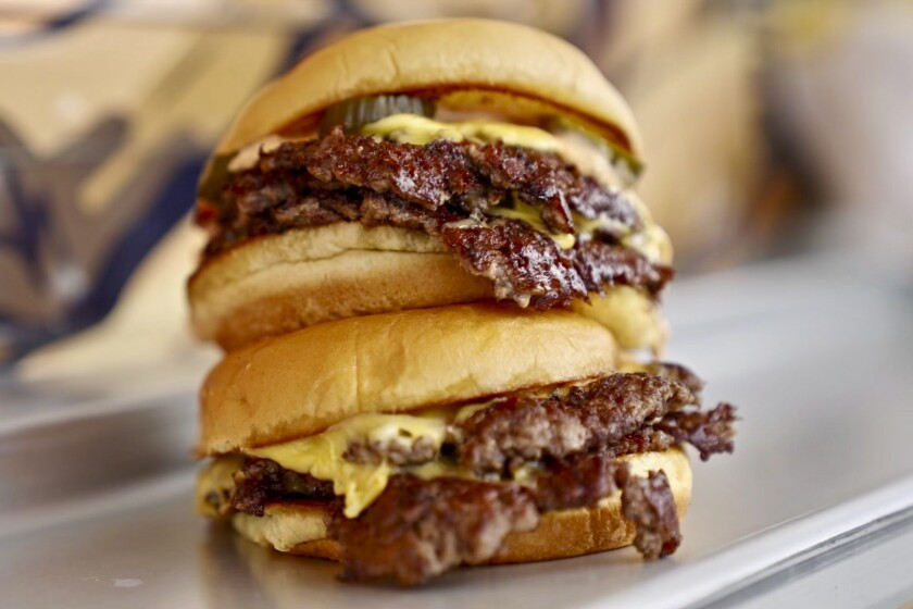 A photo of two Heavy Handed double cheese burgers stacked on top of each other.
