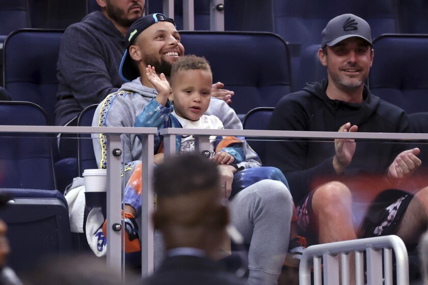 Golden State Warriors' Stephen Curry and his son, Canon, watch the Warriors play against the Sacramento Kings during a California Classic NBA summer league basketball game Saturday, July 2, 2022, in San Francisco. (Scott Strazzante/San Francisco Chronicle via AP)