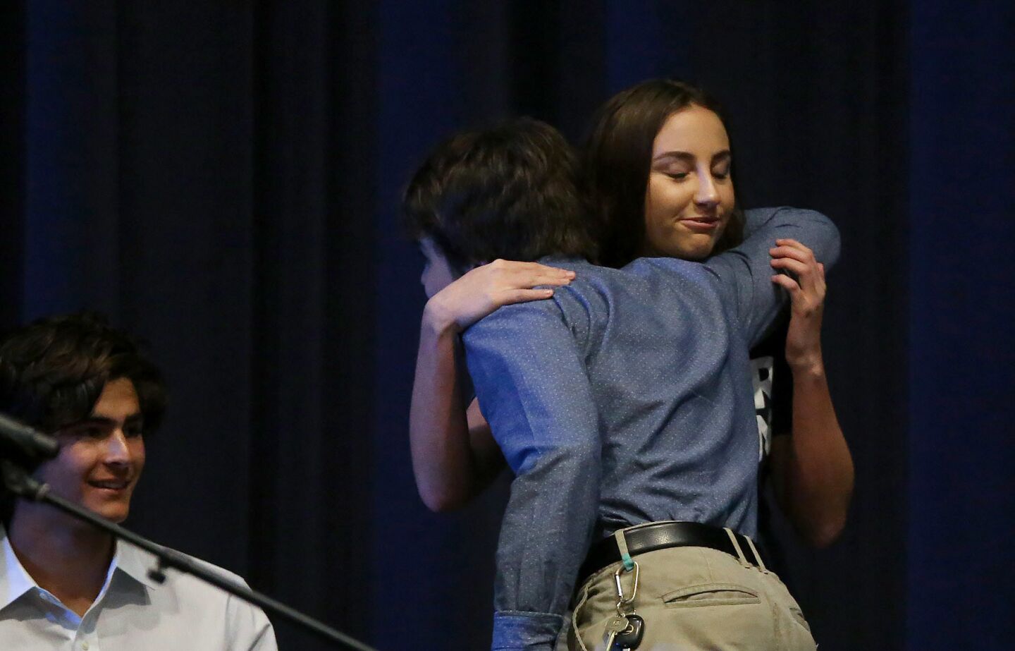 Newport Harbor High School students Gina Leaman and Max Drakeford embrace after she spoke at Monday's town hall-style meeting at the school.
