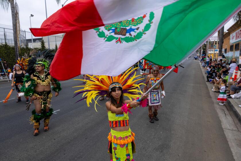 East Los Angeles, CA - September 15: Crystal Ayon, 14, of Whittier, waves a large Mexican flag during the East L.A. Mexican Independence Day Parade along East Cesar E. Chavez Avenue on Sunday, Sept. 15, 2024 in East Los Angeles, CA. (Brian van der Brug / Los Angeles Times)