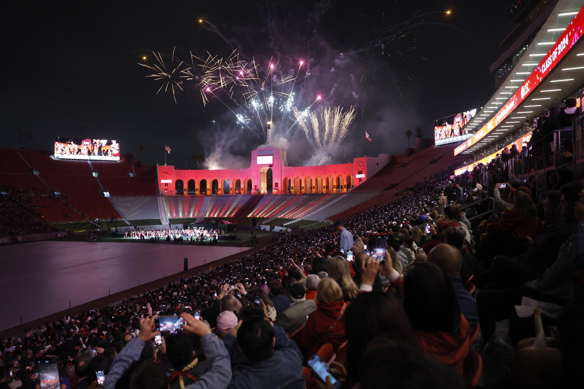 Spectators cheer and snap photos as fireworks go off at the "Trojan Family Graduate Celebration" at the Coliseum