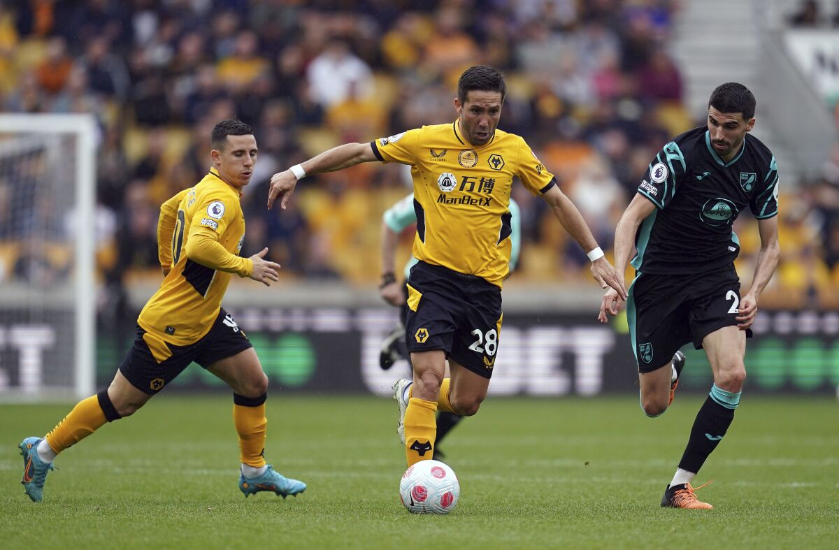 Wolverhampton Wanderers' Joao Moutinho, centre and Norwich City's Pierre Lees-Melou,right, battle for the ball, during the English Premier League soccer match between Wolverhampton Wanderers and Norwich City at Molineux Stadium, Wolverhampton, England, Sunday May 15, 2022. (Nick Potts/PA via AP)