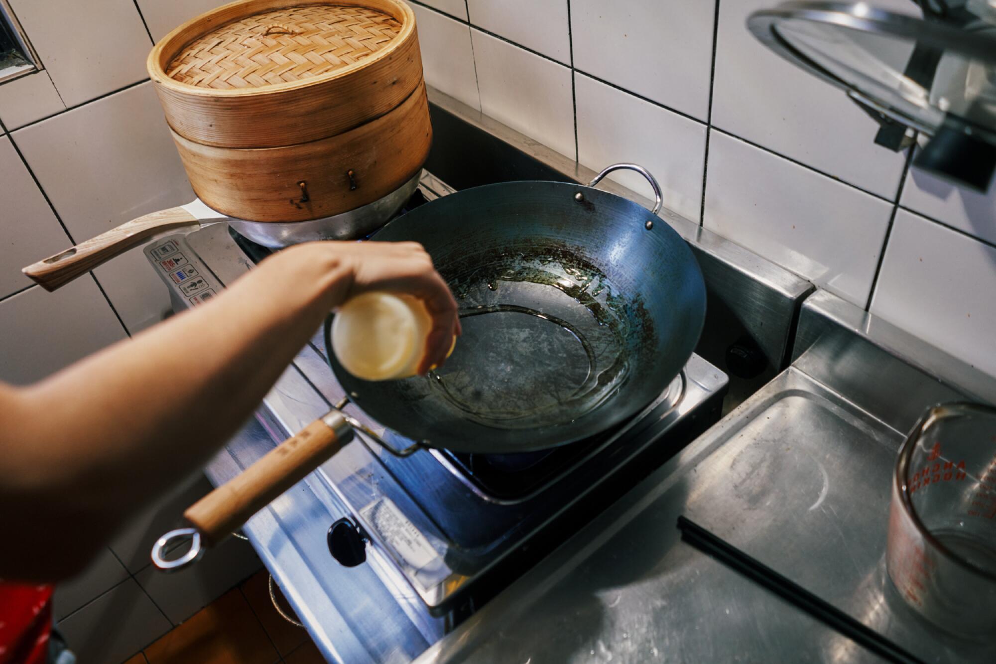 Heating oil in a wok in a tiled kitchen.
