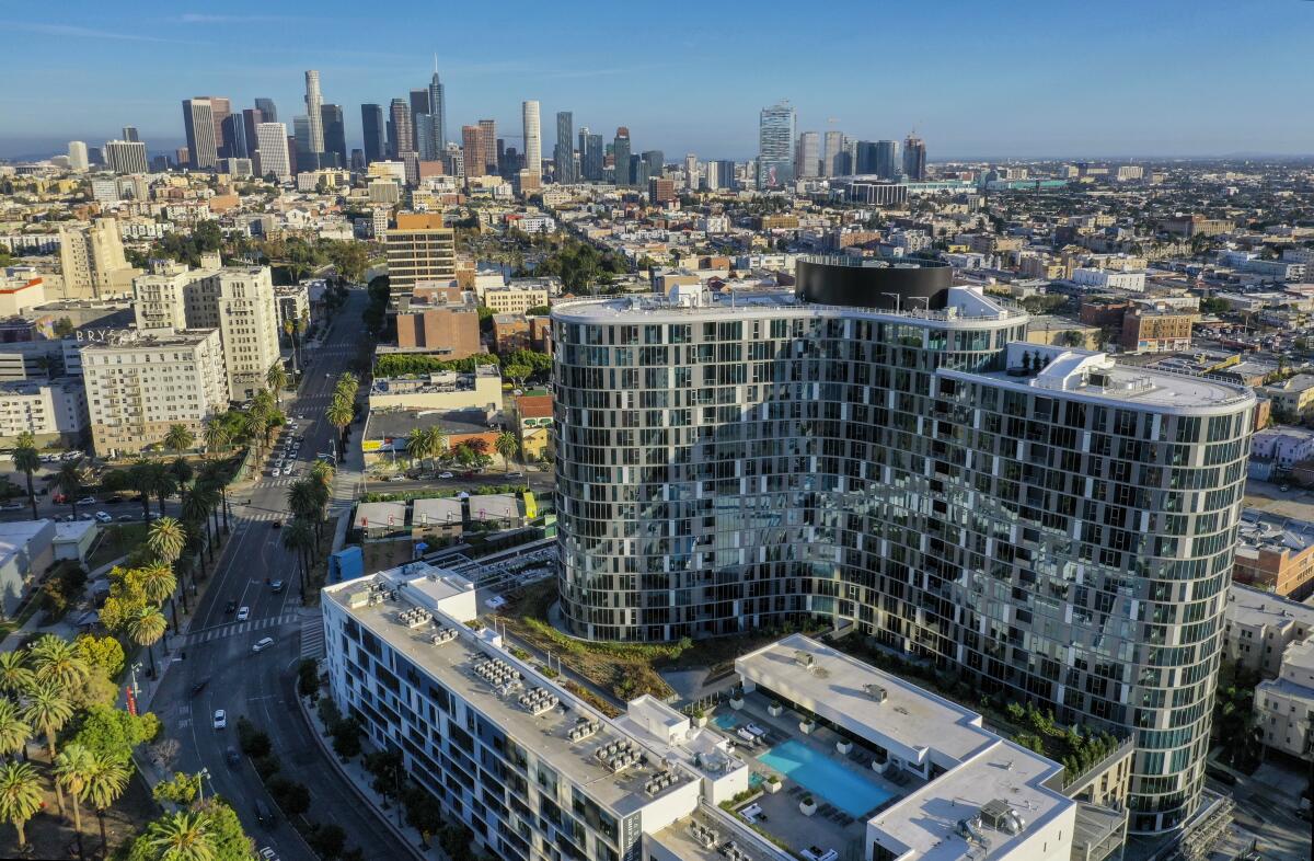 An aerial exterior view of the Kurve on Wilshire in Koreatown, with the L.A. skyline beyond. 