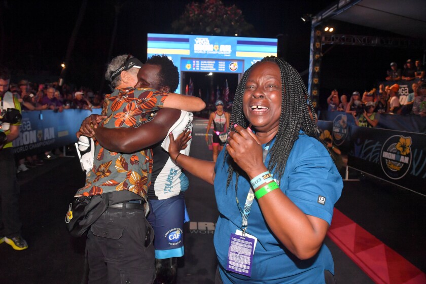 Challenged triathlete Roderick Sewell, center, gets a hug at the finish line from Challenged Athletes Foundation co-founder Bob Babbitt while his mother, Marian Jackson, right, cries with relief at the 2019 Ironman World Championship in Hawaii on Oct. 12.