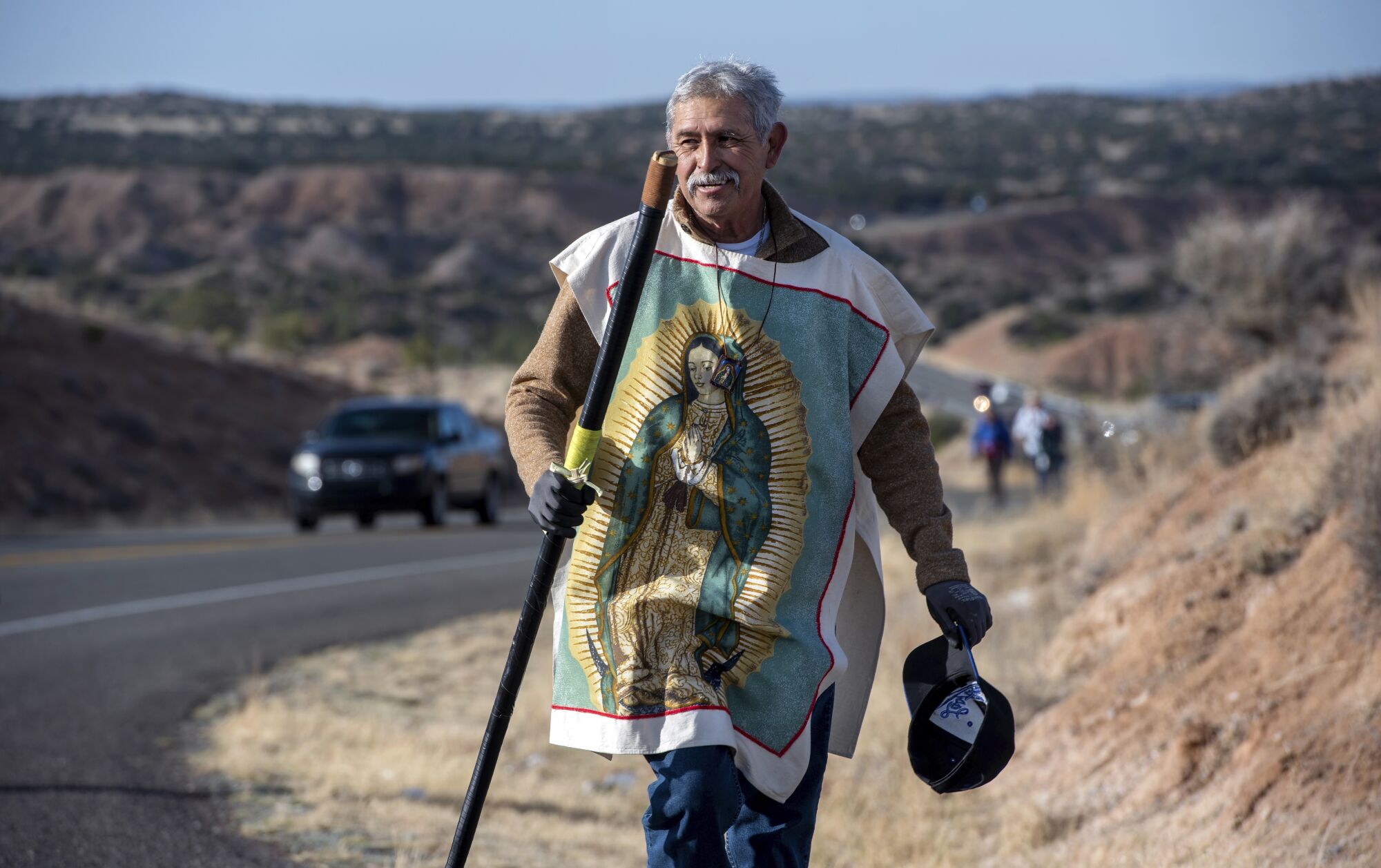 Jesus Valdez walks along Santa Fe County Road 98 on a sunny day