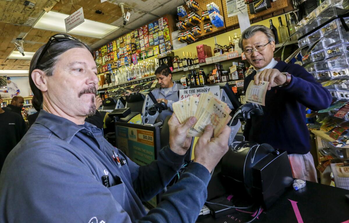 Mark Nelson, left, shows off $460 worth of Powerball lottery tickets he bought at Bluebird Liquor, a shop with a reputation for lottery luck, in Hawthorne. At right is the owner of the liquor store, James Kim. (Irfan Khan / Los Angeles Times)
