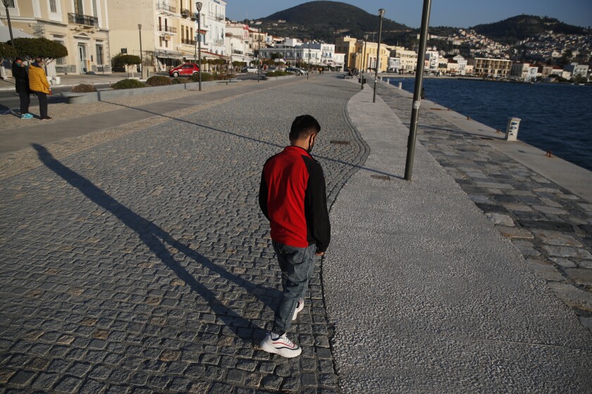 A man walks along a mostly deserted waterfront road