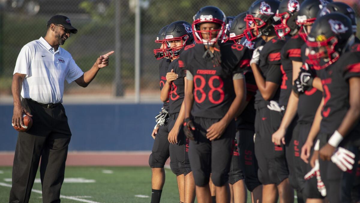 Village Christian offensive line coach Todd McNair talks with players on the field in Burbank on Friday.