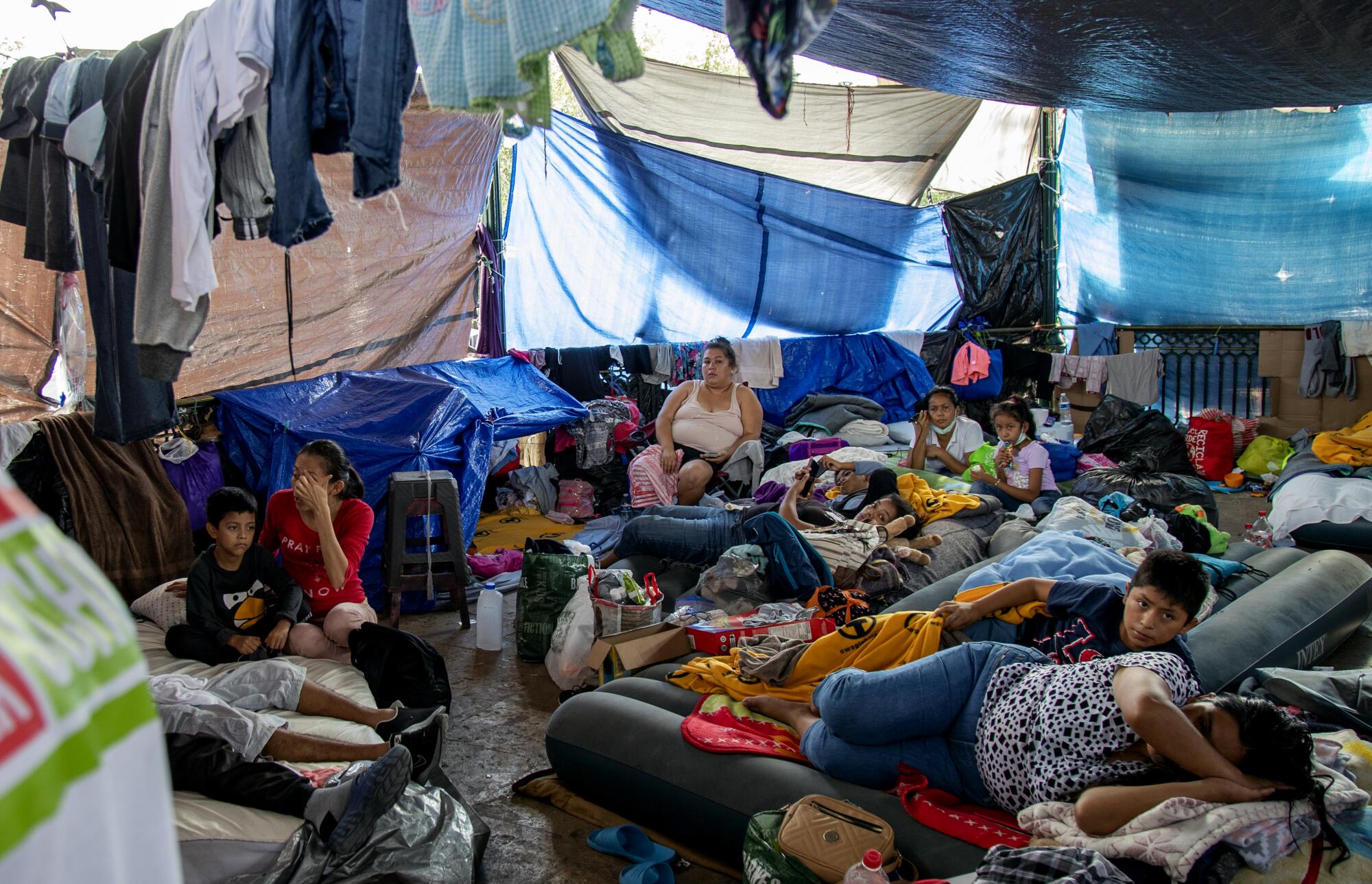 Asylum seekers sleep on air mattresses under tarps