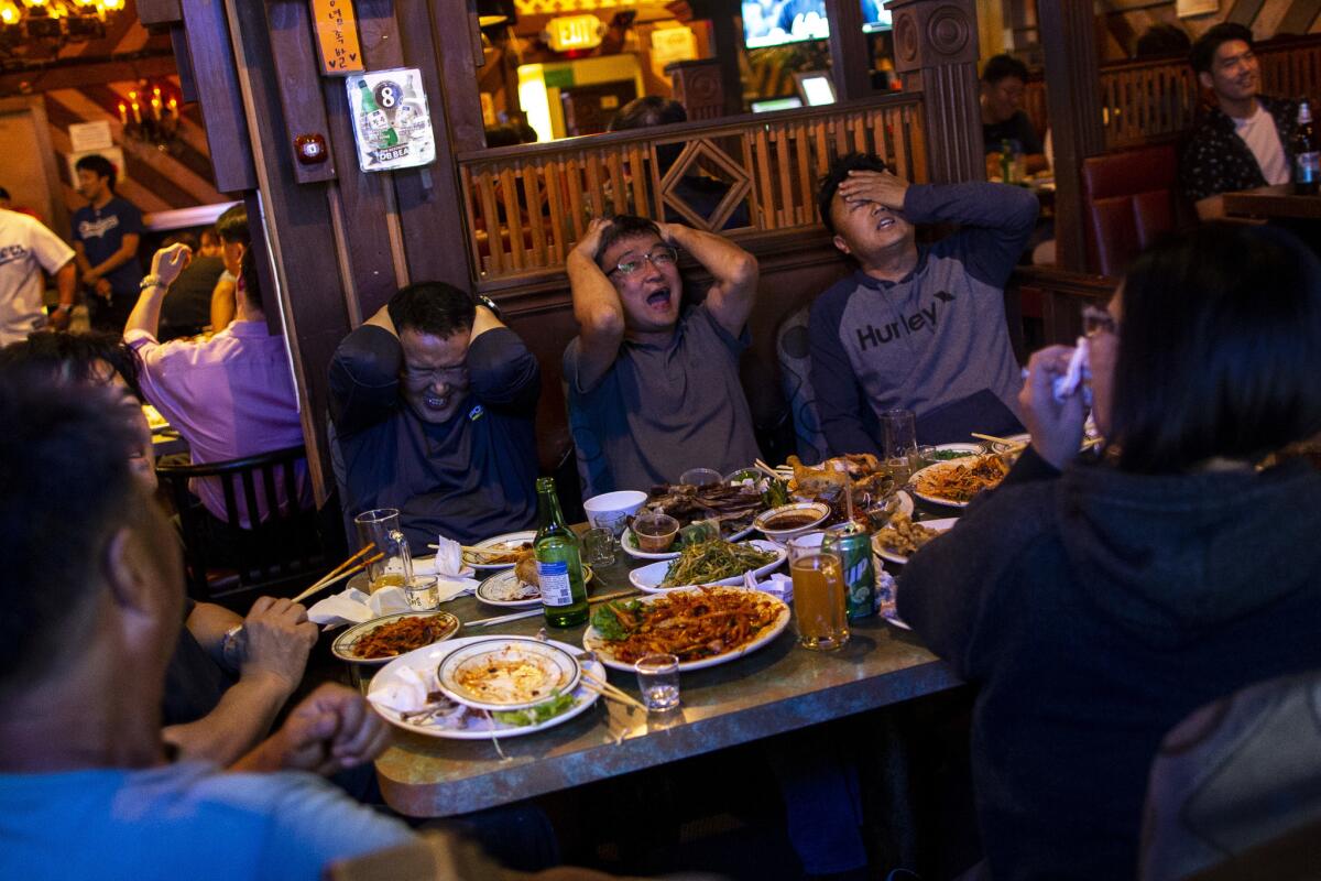 Patrons react to the broadcast of Game 1 of the National League Division Series between the Dodgers and the Atlanta Braves at OB Bear in Koreatown. (Kent Nishimura / Los Angeles Times)