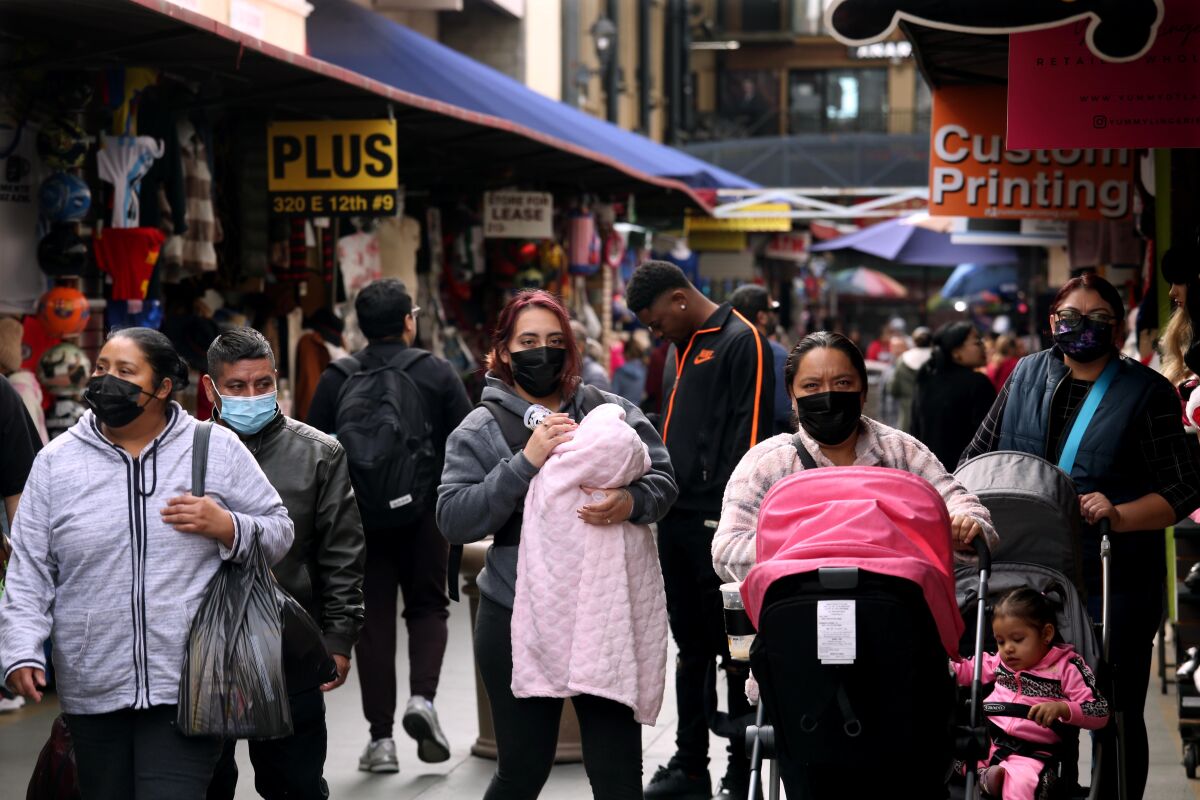 Shoppers, some wearing masks, make their way along Santee Alley in Los Angeles.