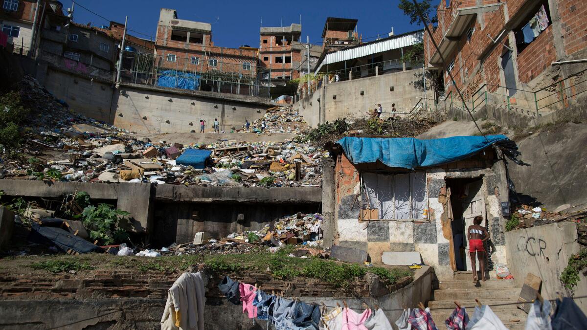 A woman enters her shack on a hillside next to a landfill in the Mangueira slum of Rio de Janeiro in 2014. (Leo Correa / Associated Press)