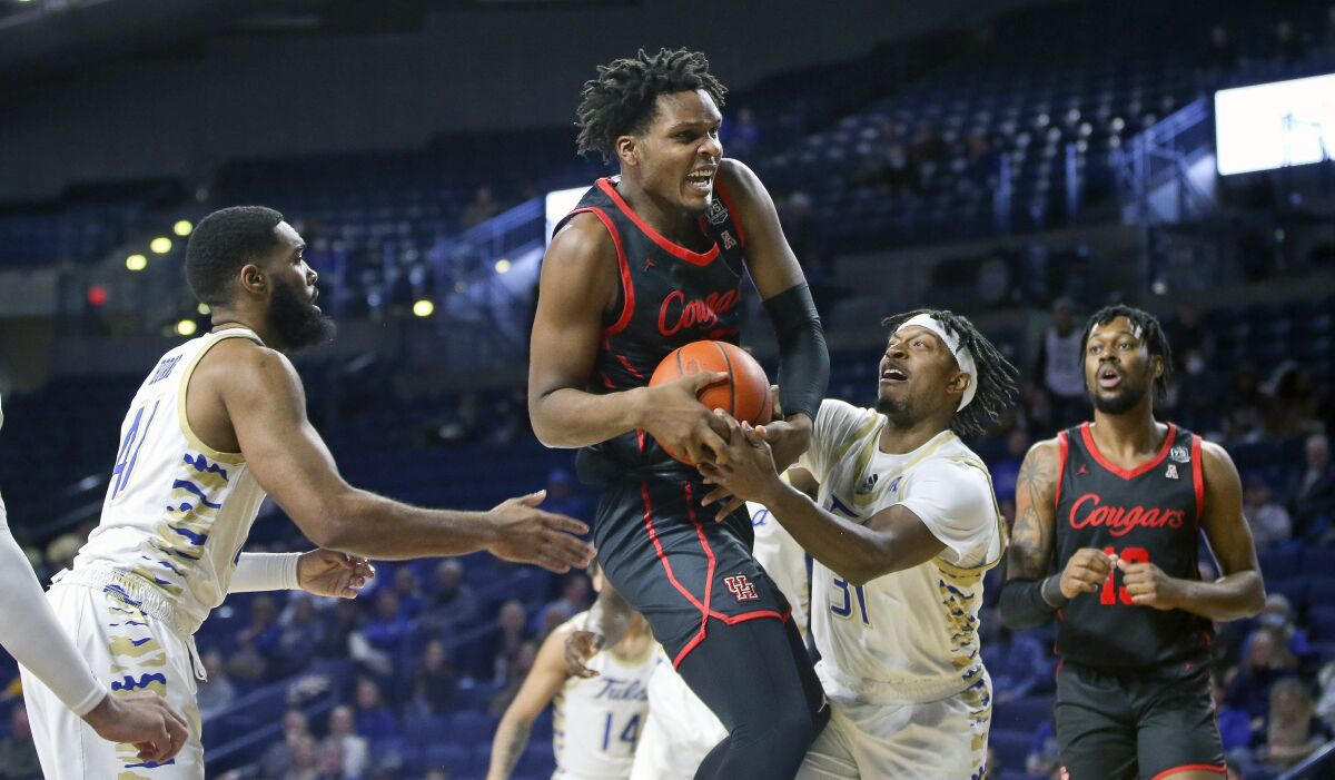 Houston's Josh Carlton brings down a rebound against Tulsa's Jeriah Horne, left, and LaDavius Draine during the first half of an NCAA college basketball game in Tulsa, Okla. on Saturday, Jan. 15, 2022. Houston's J'Wan Roberts is at far right. (AP Photo/Dave Crenshaw)