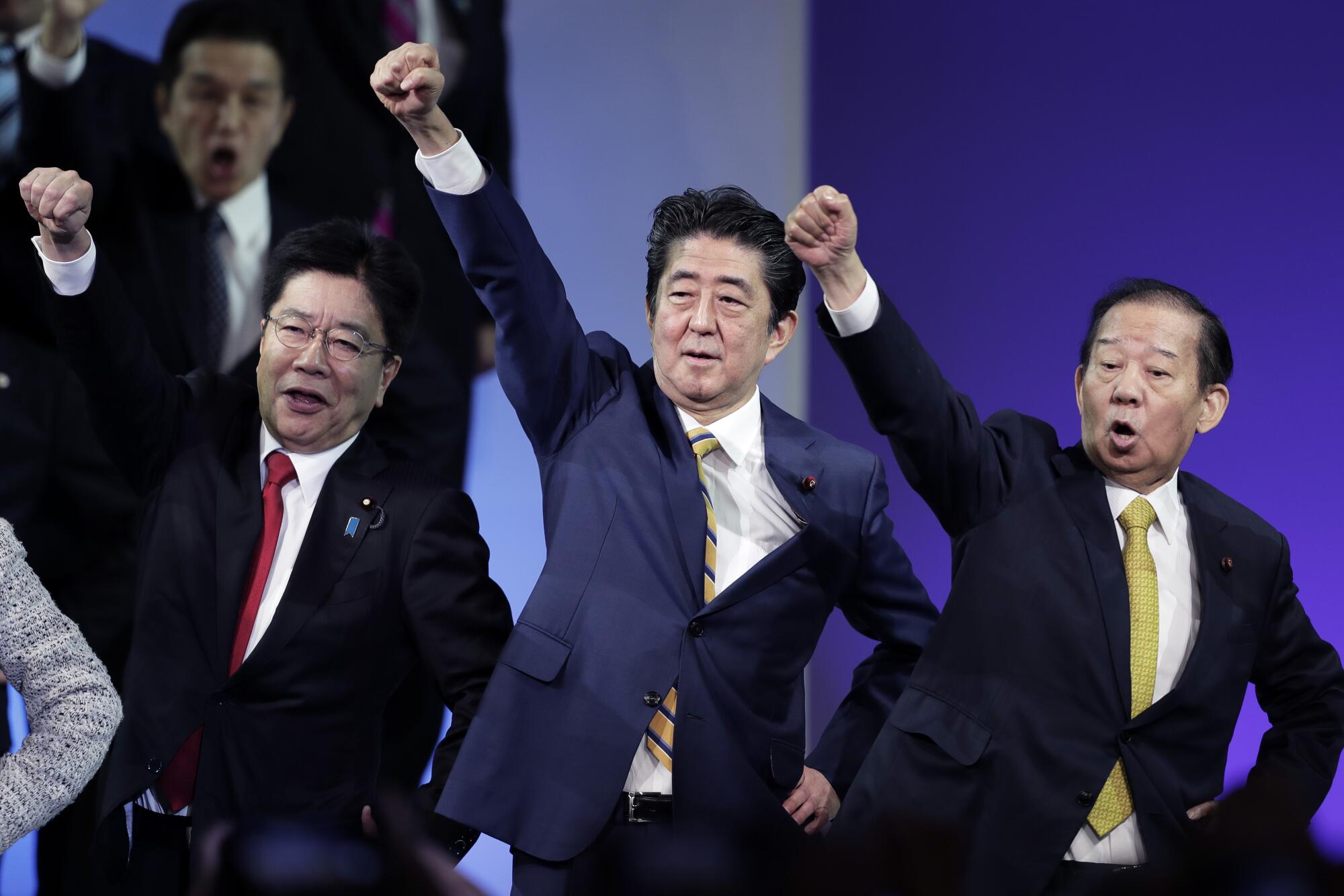 Shinzo Abe, Japan's prime minister and president of the Liberal Democratic Party (LDP), center, raises his fist