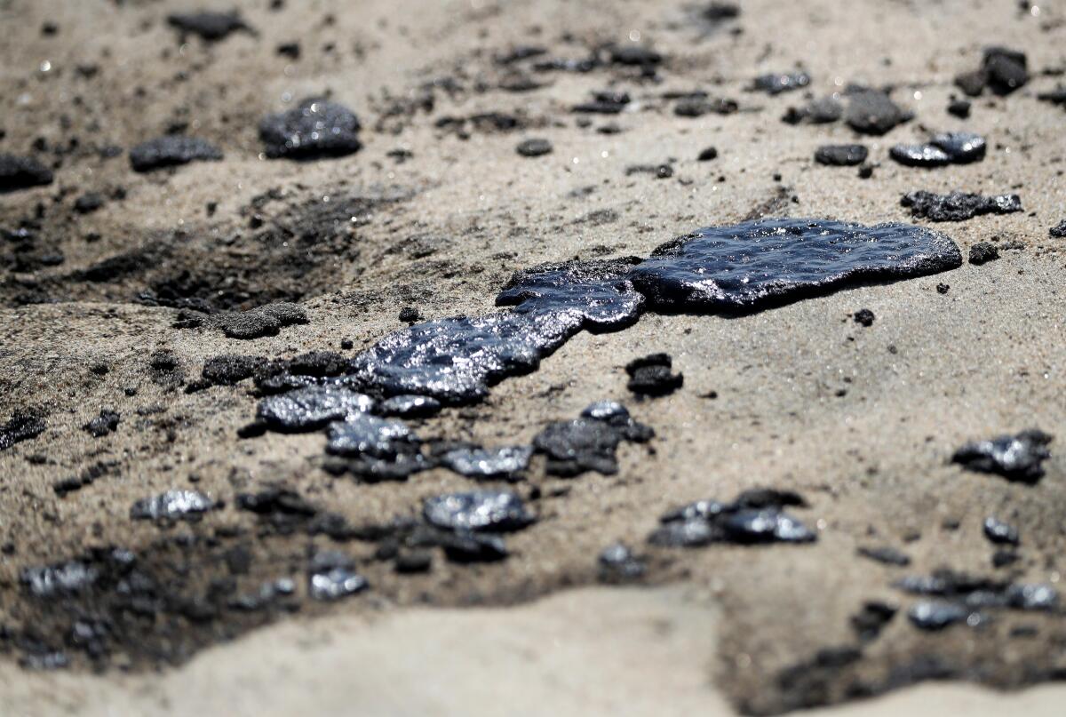 Crude oil covers the sand at the mouth of the Santa Ana River in Newport Beach on Sunday.