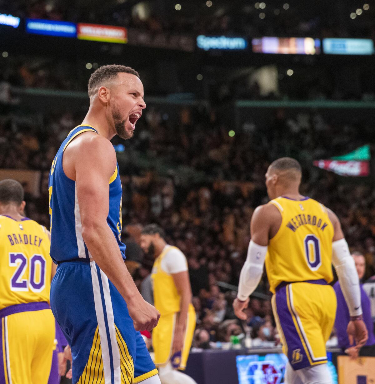 Warriors guard Stephen Curry, who had a triple-double, celebrates as Lakers guard Russell Westbrook walks away.