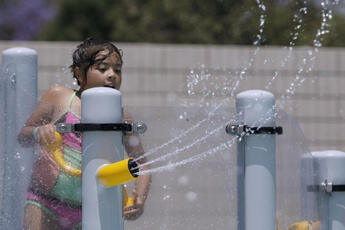 A young swimmer plays with the water cannons during the grand opening of the Verdugo Pool in Burbank in June.