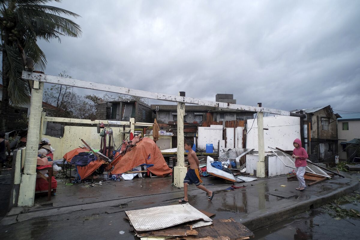 Children pass by homes damaged by strong winds as Typhoon Kammuri slammed Legazpi city in the province of Albay, southeast of Manila, on Tuesday.