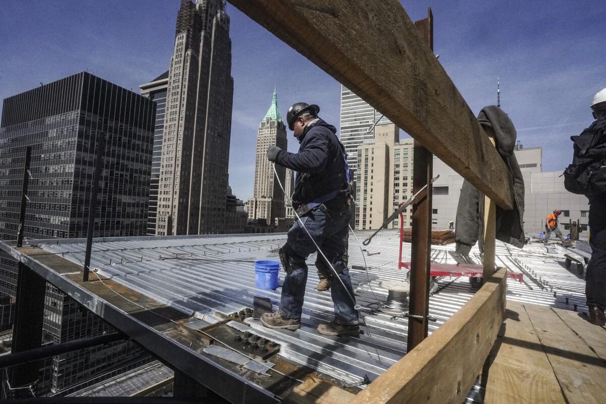 Construction workers install roofing on a high-rise in Manhattan's financial district.