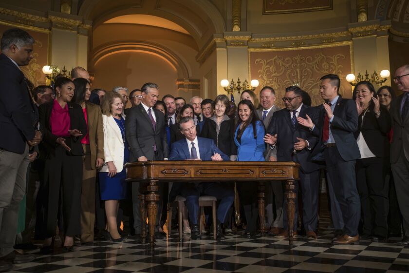 Gov. Gavin Newsom signs a bill aimed at addressing gas price gouging while surrounded by legislators and state officials in the Capitol rotunda, Tuesday, March 28, 2023, in Sacramento, Calif. (Xavier Mascareñas/The Sacramento Bee via AP)