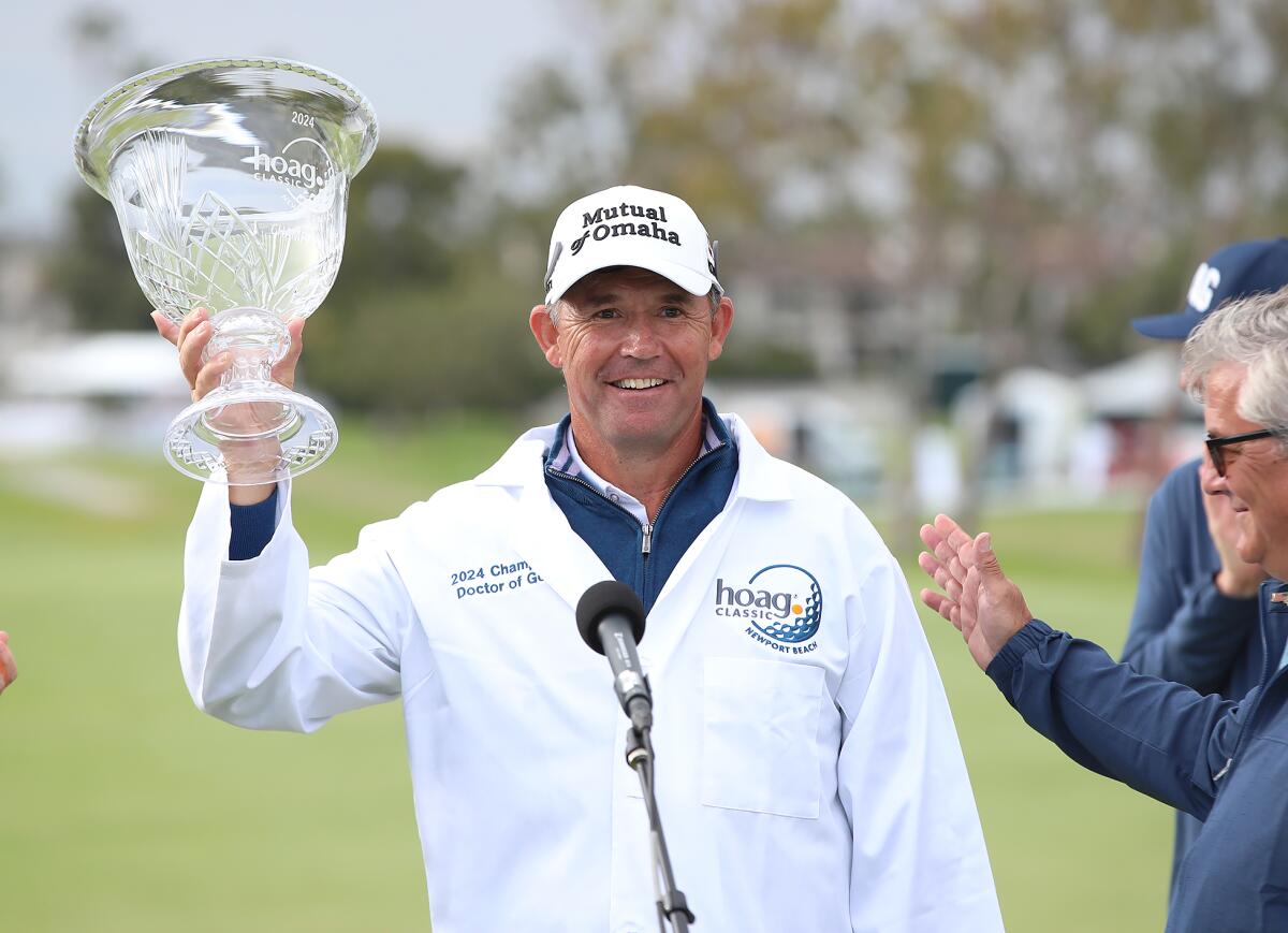 Wearing the 2024 Doctor of Golf jacket, Champion Padraig Harrington raises the trophy the after winning the Hoag Classic.