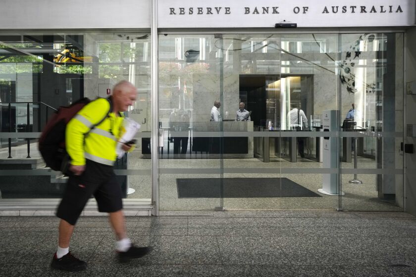 A postal worker walks past the Reserve Bank of Australia in Sydney, Tuesday, Dec. 6, 2022. Australia's central bank has raised its benchmark interest rate by a quarter-point to 3.1% as it continues to battle inflation. (AP Photo/Rick Rycroft)