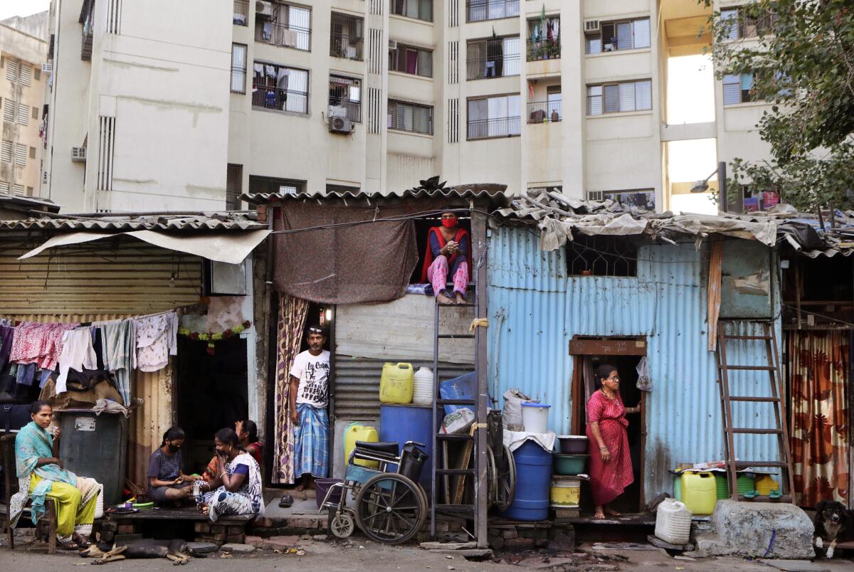 Residents of Dharavi rest beside their homes Friday during India's nationwide lockdown.